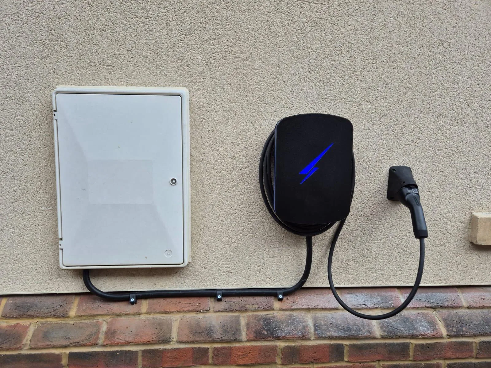 Tethered EV charging point installed next to a meter box on a house wall