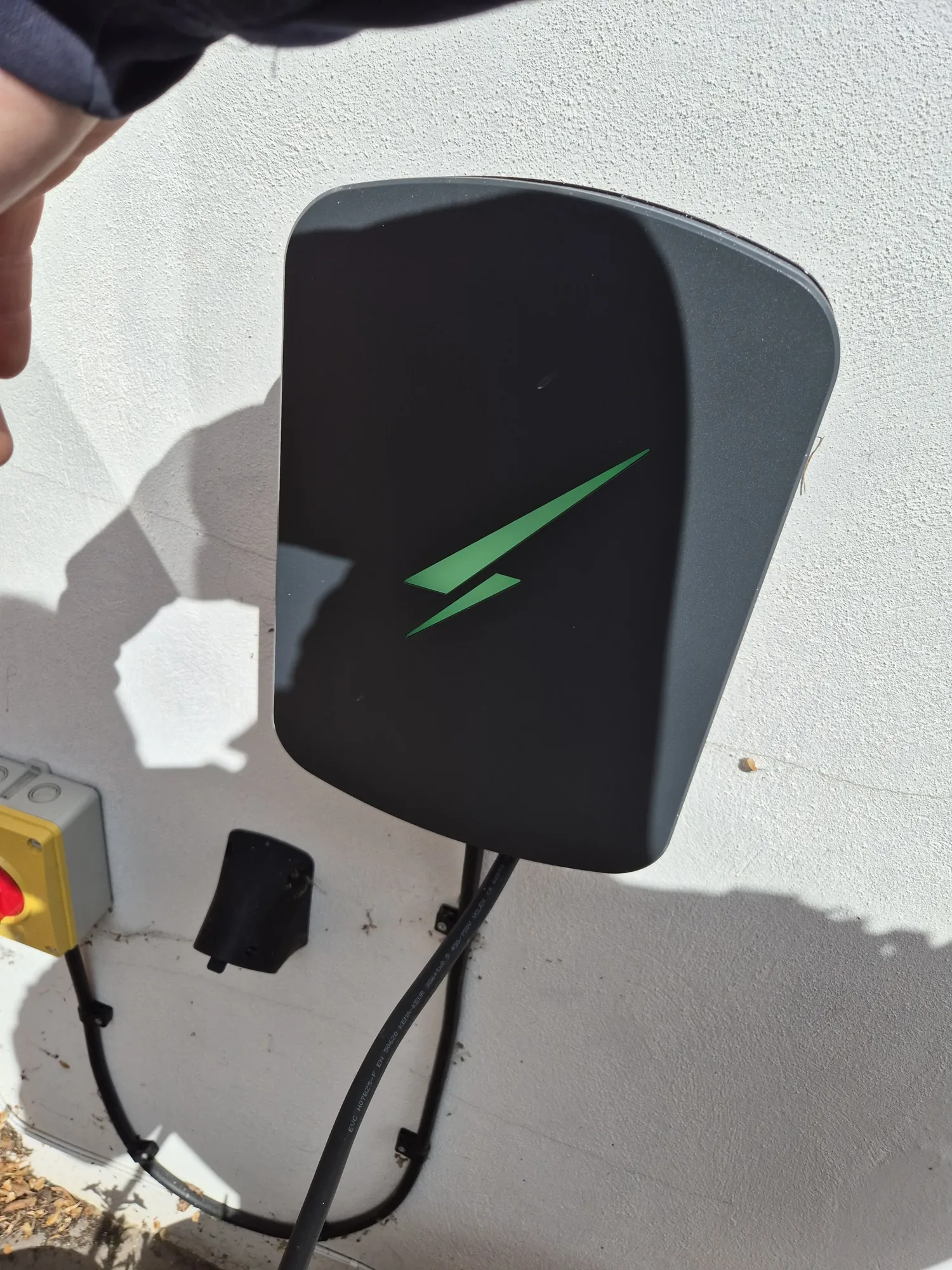 Newly installed EV charging point with isolator switch on a rendered wall